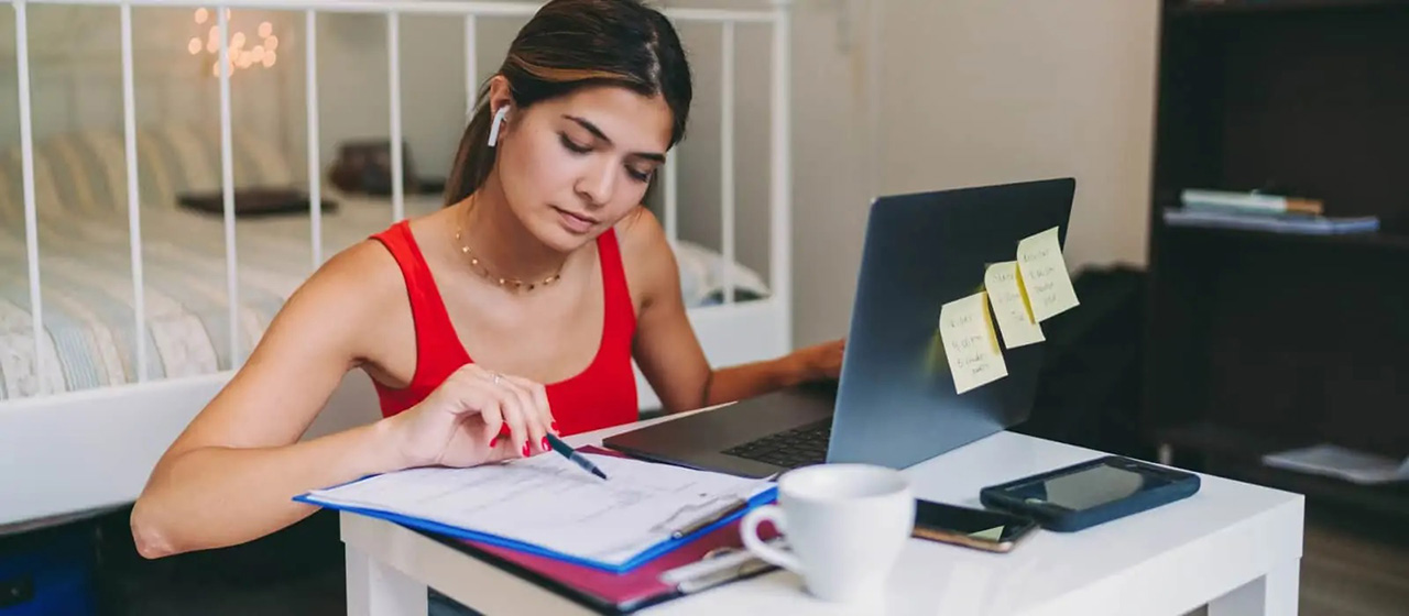 Woman reading paper on clipboard at her desk