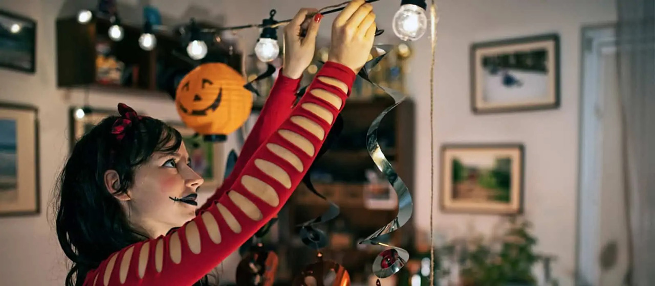 Female in a red costume hanging halloween decoration lights