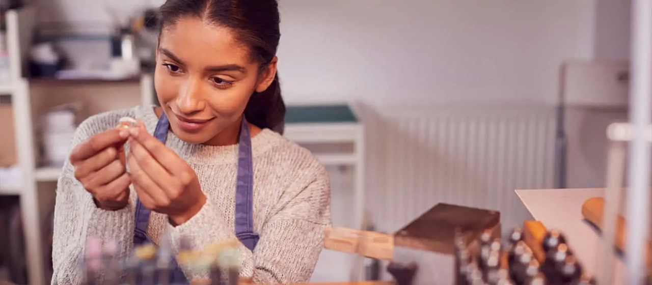 Women holding piece of jewelry with both hands in an apron