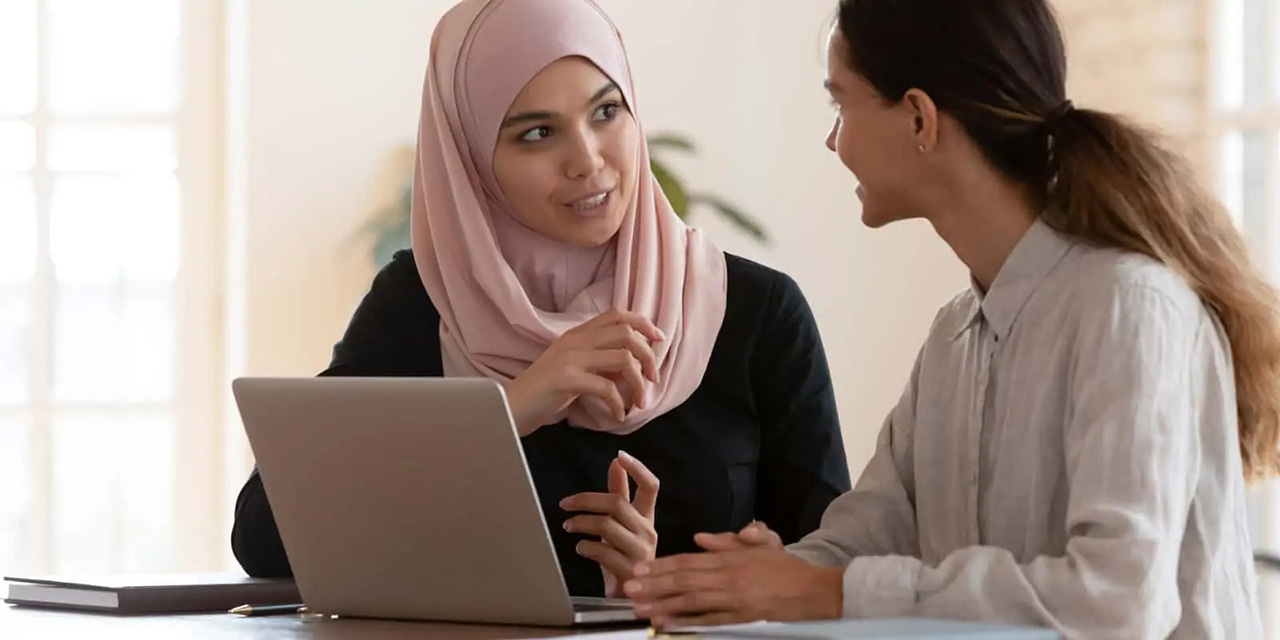 Two women talking with a laptop open in front of them