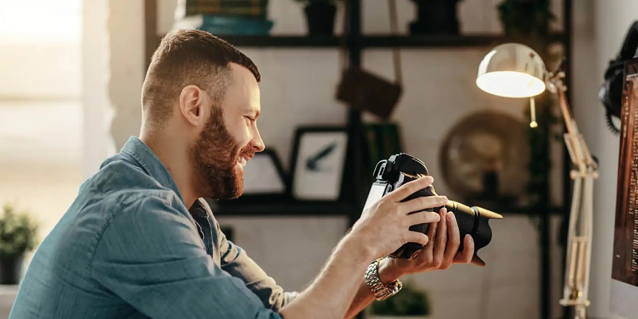 Man holding camera and smiling while looking at camera screen