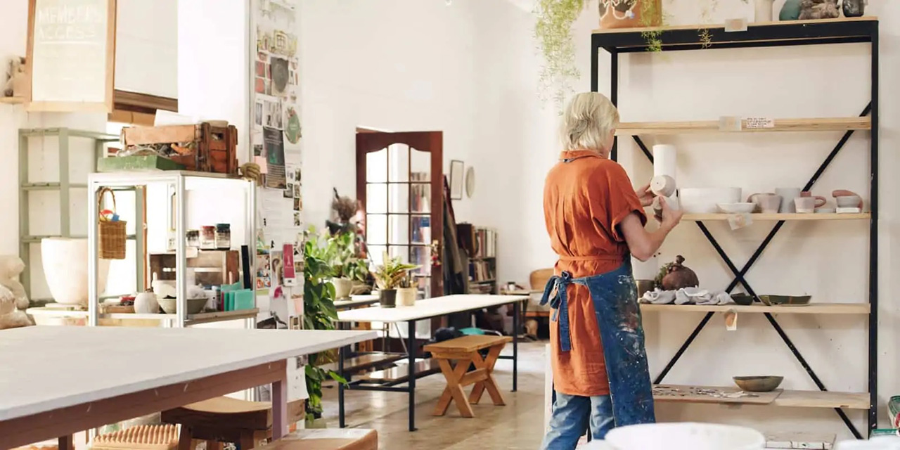 Woman in her own pottery shop wearing an apron