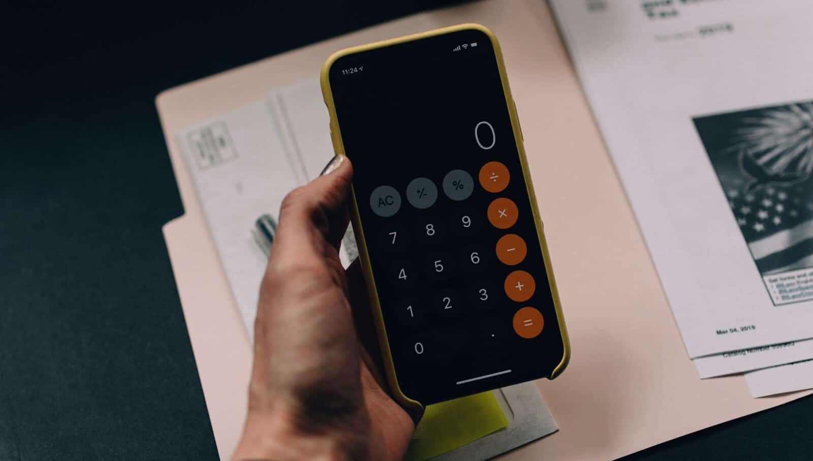 Woman holding calculator above manilla folder with tax forms in it