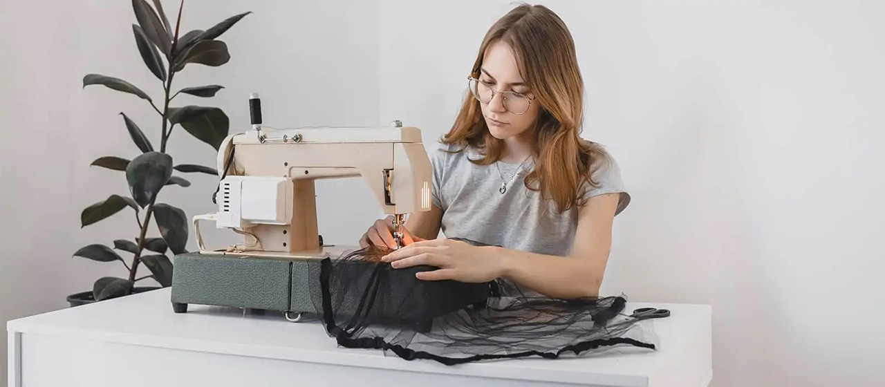 Female teen using sewing machine next to plant