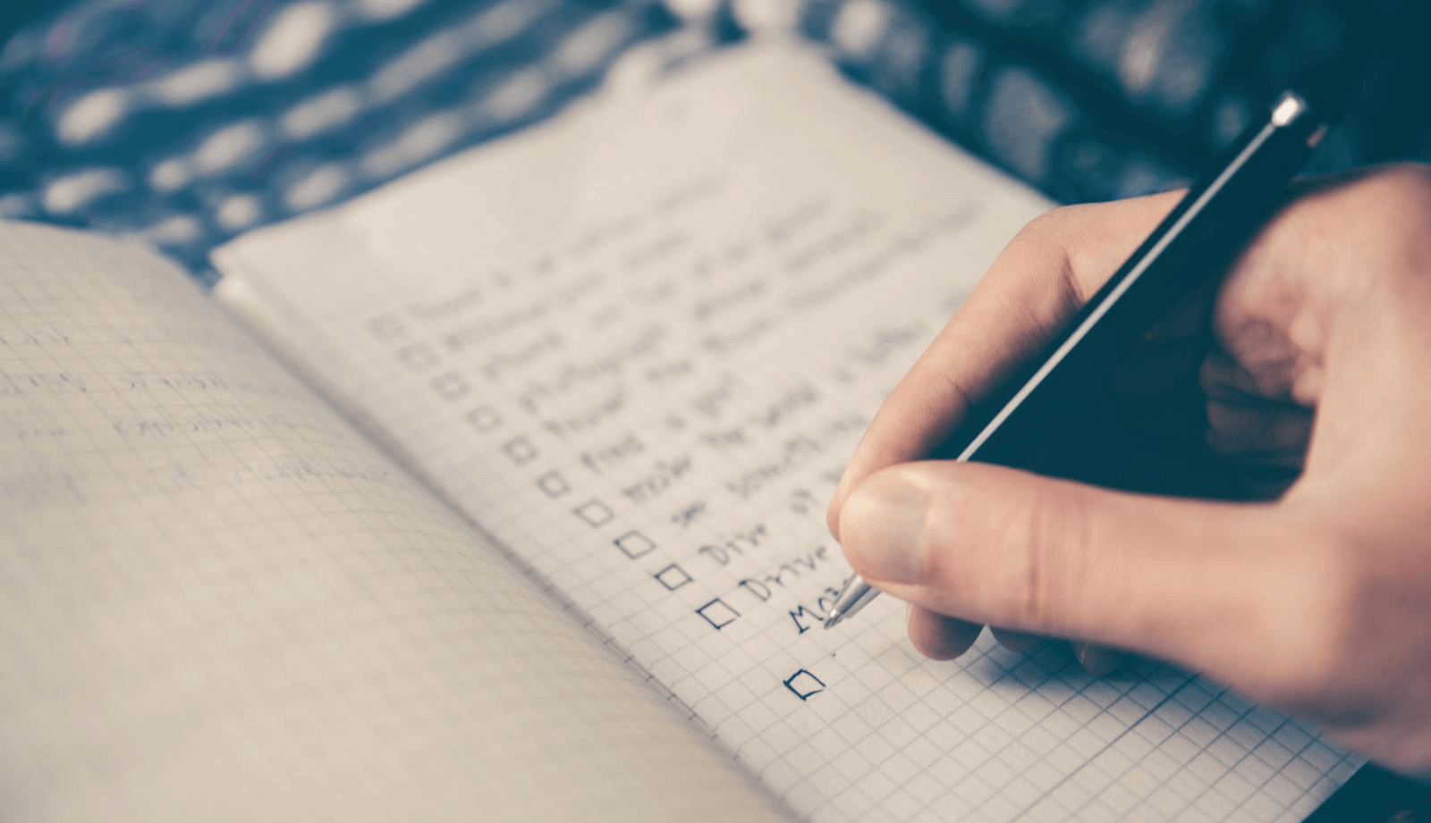 Person writing a check list in book