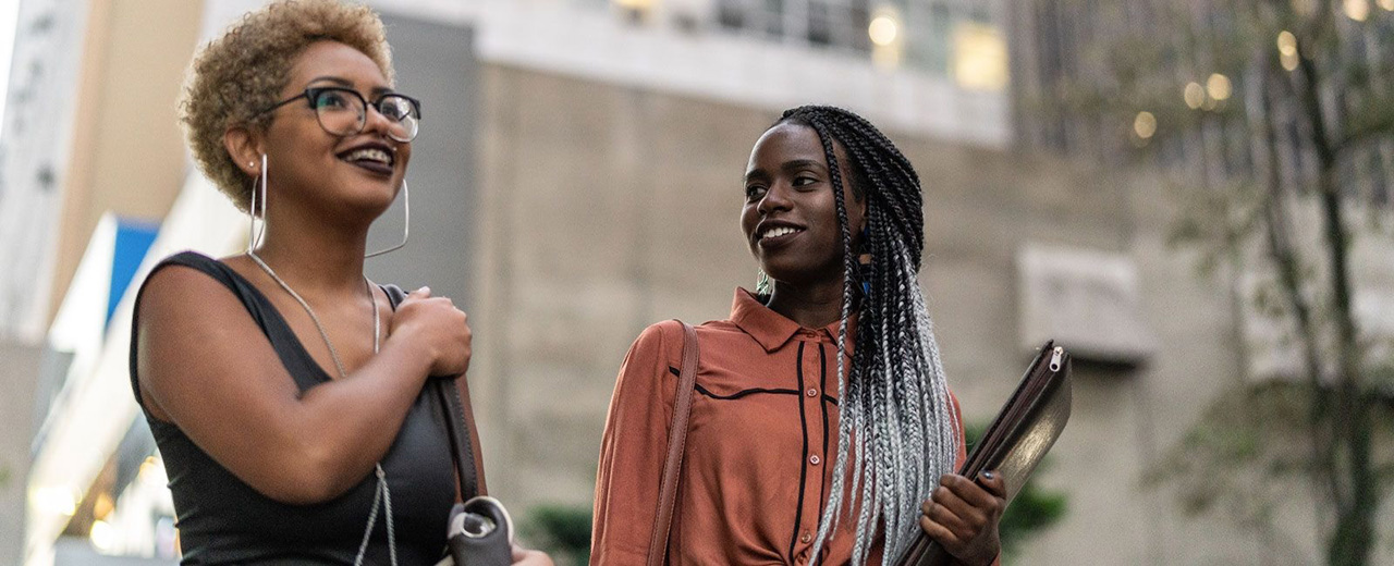 Two women talking outside in a metropolitan city