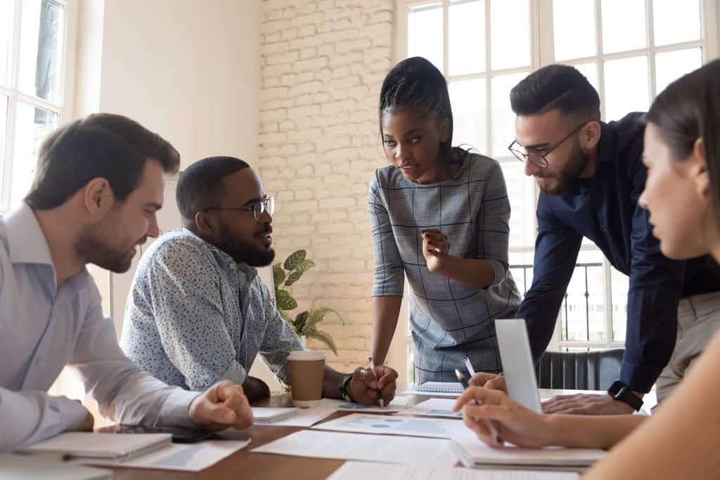 5 people sitting at a table hosting a meeting.