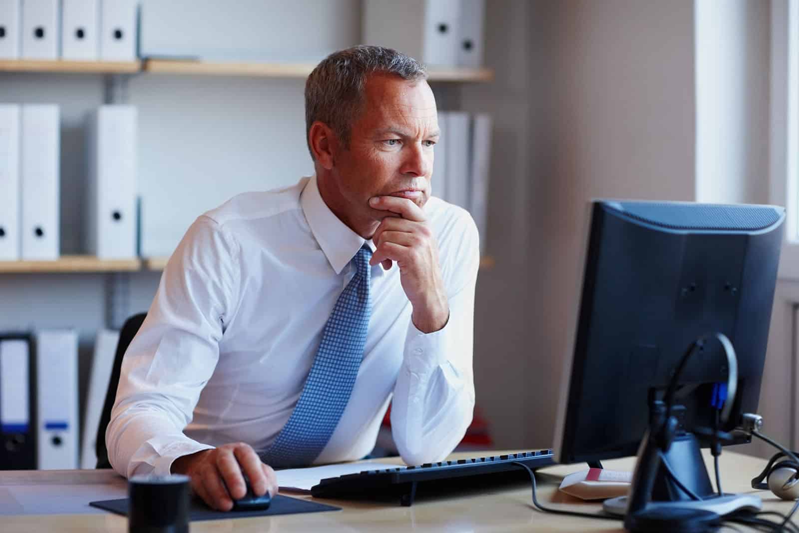 Man in a suit sitting in front of a computer.