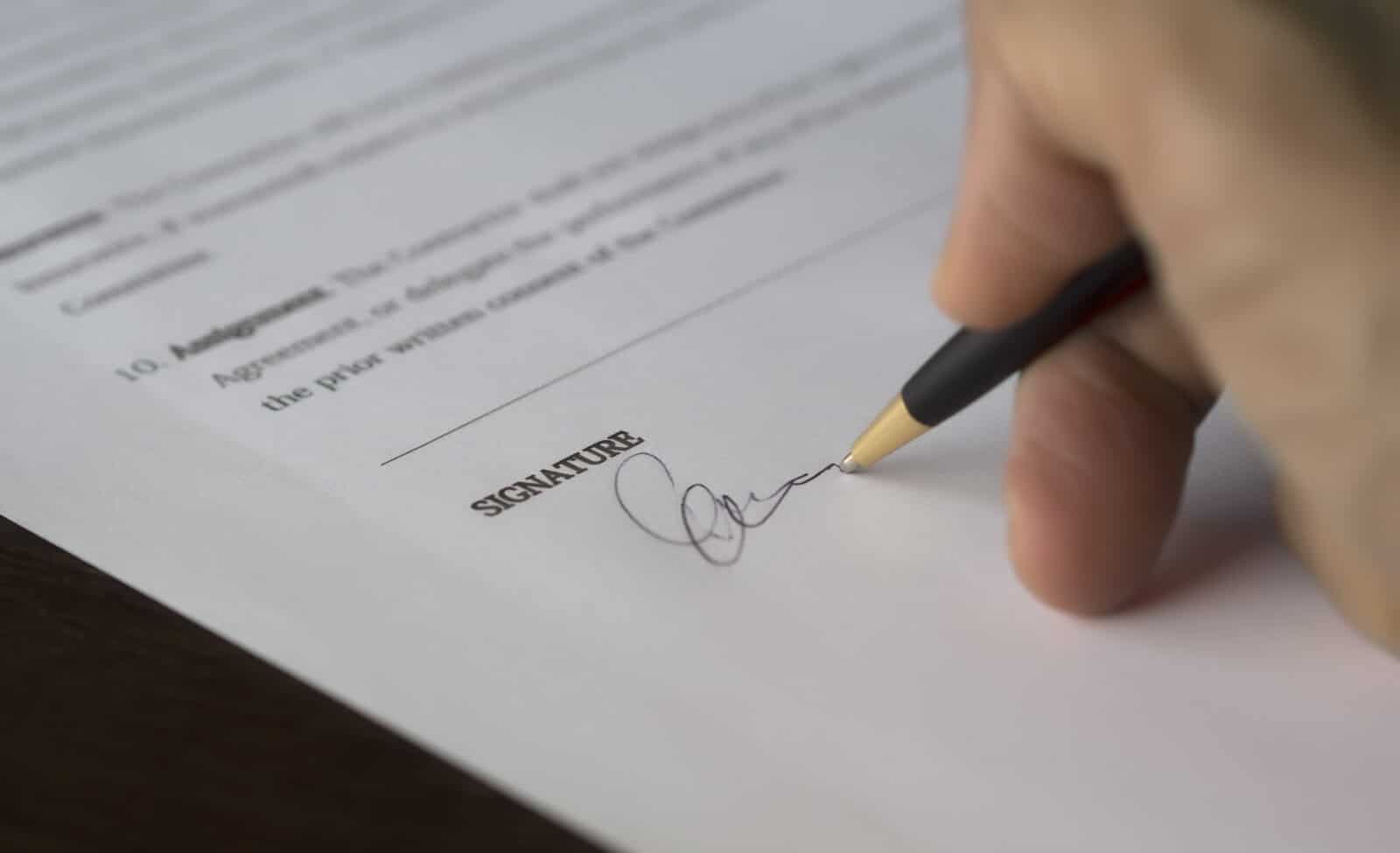 Person signing document with black pen